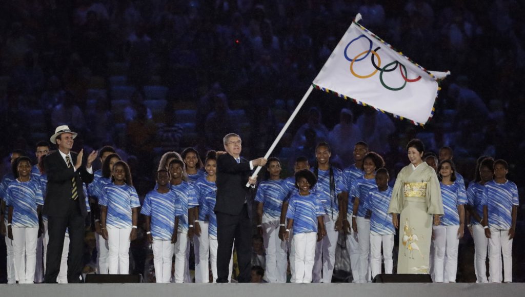 Rio de Janeiro, 2016. augusztus 22. Thomas Bach, a Nemzetközi Olimpiai Bizottság elnöke meglengeti az olimpiai zászlót, mielõtt átadná azt Juriko Koikének, a 2020-as nyári olimpiát rendezõ Tokió kormányzójának (j) a XXXI. nyári olimpiai játékok záróünnepségén a Rio de Janeiró-i Maracana Stadionban 2016. augusztus 21-én. Balra Eduardo Paes, Rio de Janeiro polgármestere. (MTI/AP/Matt Dunham)